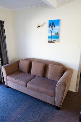 a brown couch sitting in a living room at Tairua Shores Motel in Tairua
