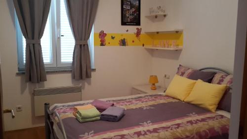 sypialnia z łóżkiem z kolorowymi poduszkami i oknem w obiekcie Maristela w Rovinj
