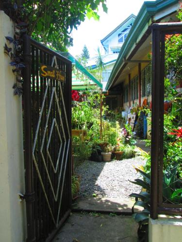 Una puerta a un jardín con un cartel. en Small House - Baguio en Baguio