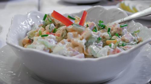 a white bowl filled with a salad on a plate at Noclegi Sebastian w Centrum in Ustrzyki Dolne