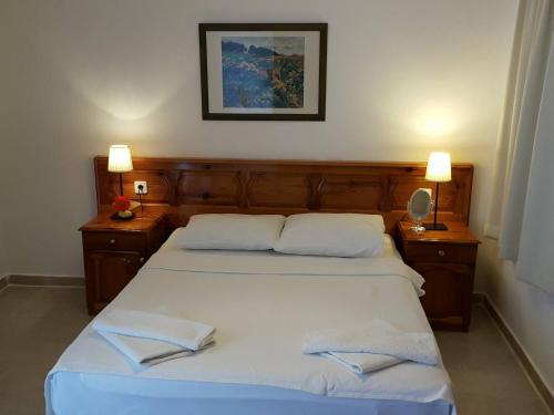 um quarto com 2 camas com lençóis brancos e 2 candeeiros em Dolphin Apartments em Fethiye