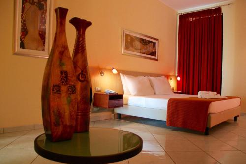 Meridian Hotel في جارديا بيمونتيس تيرمي: غرفة الفندق بسرير وطاولة زجاجية