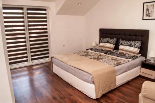 a bedroom with a large bed and wooden floors at Apartment Elegant in Velingrad