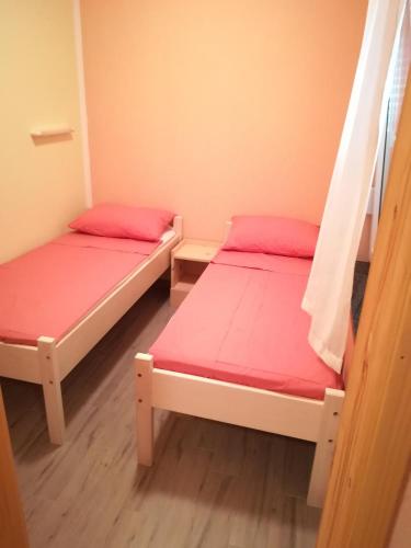 two beds in a small room with pink sheets at Cinema House Single & Double Rooms & Studio Apartments in Pula