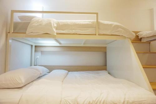 a bedroom with two bunk beds with white sheets at Boon Street Hostel in Bangkok