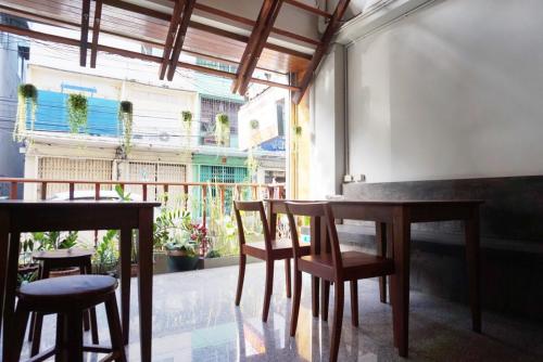 a dining room with tables and chairs and a balcony at Boon Street Hostel in Bangkok