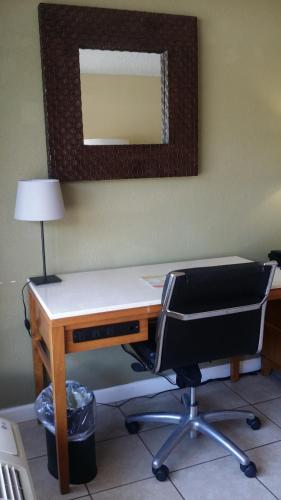 an office with a desk and a chair and a mirror at Days Inn by Wyndham Cocoa Cruiseport West At I-95/524 in Cocoa