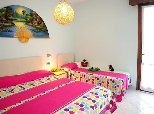 ビビオーネにあるAzalee Belmare Apartmentsのピンクとカラフルなシーツが備わる客室のベッド2台