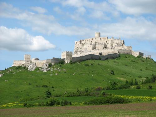 a castle on top of a green hill at Penzion Chalupka in Spišské Podhradie