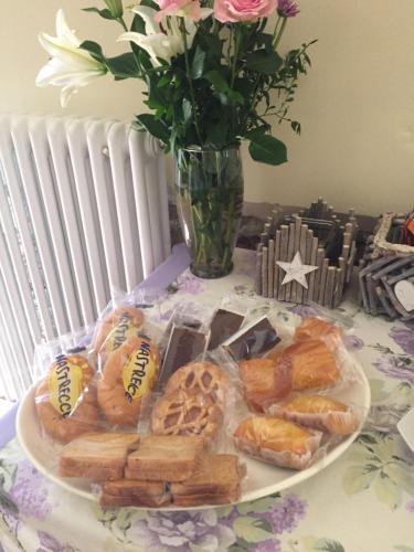 a plate of pastries on a table with a vase of flowers at B&B Happiness in the Country in Brescello