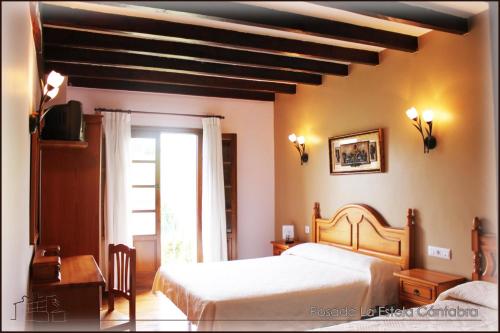 a bedroom with a bed and a desk and a window at Posada La Estela Cántabra in Toñanes