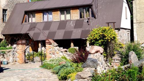 a home with a stone wall and a building at Guest house Jumiezis in Pļaviņas