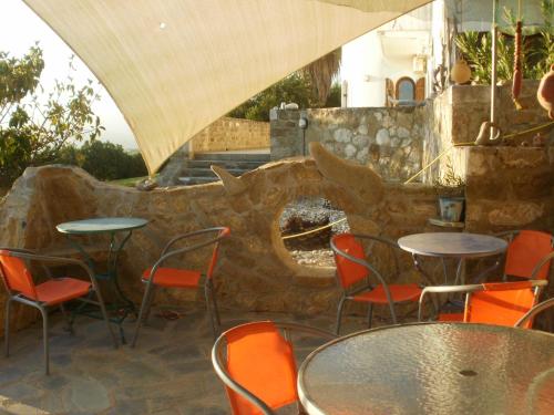 a patio with tables and chairs and a stone wall at Charly Point Villa in Methoni