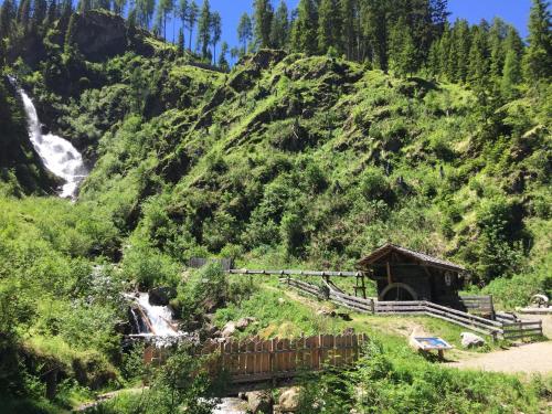 a mountain with a waterfall and a cabin on it at Ferienwohnungen Böhm in Sankt Jakob in Defereggen