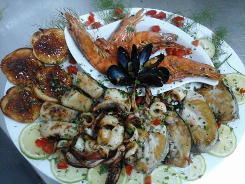 a plate of food with shrimp and other foods at Colapesce in Santa Teresa di Riva