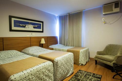 Pokój hotelowy z 2 łóżkami i krzesłem w obiekcie Gallant Hotel w mieście Rio de Janeiro