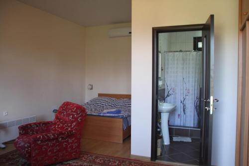 1 dormitorio con 1 cama y 1 silla roja en АМРАПХА, en Gudauta