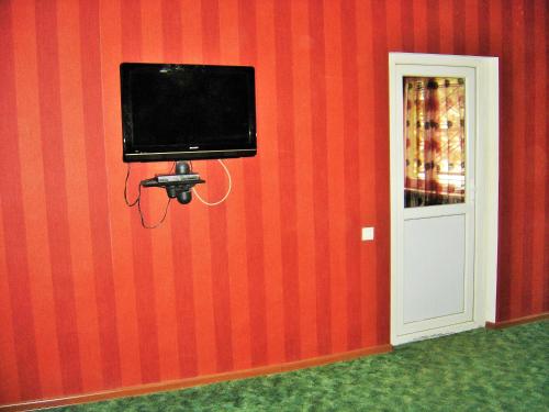 a television on a red wall with a camera at Hotel Lilo near Airport in Tbilisi City