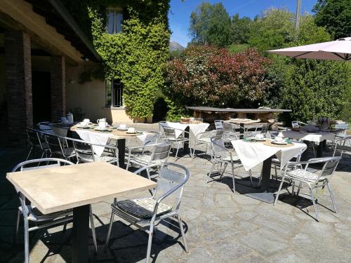 an outdoor patio with tables and chairs and an umbrella at Antica Cascina del Medico in Muzzano