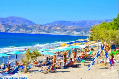 a group of people sitting on a beach with umbrellas at Heraklion Gortyn Phaistos House in Mitrópolis