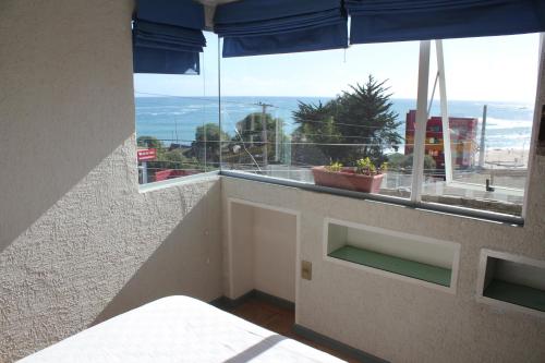 a room with a balcony with a view of the ocean at Hostal Boutique F in El Quisco