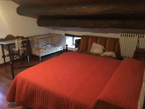 BalzeにあるLocanda di Federicoのベッドルーム(赤いベッド1台、ベビーベッド1台付)