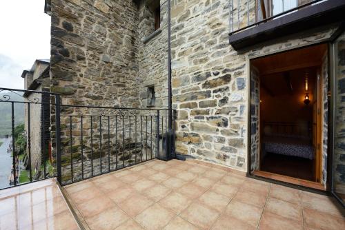 uma varanda de um edifício de pedra com uma porta em Habitación El Mirador Casa Cajal em Torla