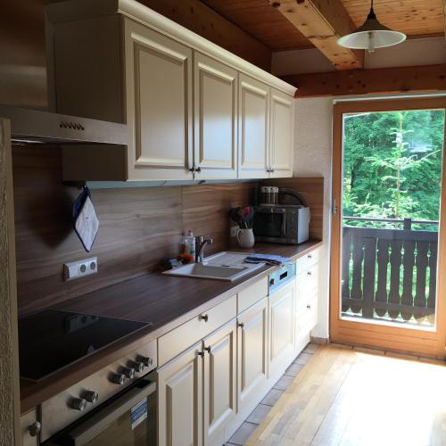a kitchen with white cabinets and a sink and a window at Kleine Ahornau in Schladming