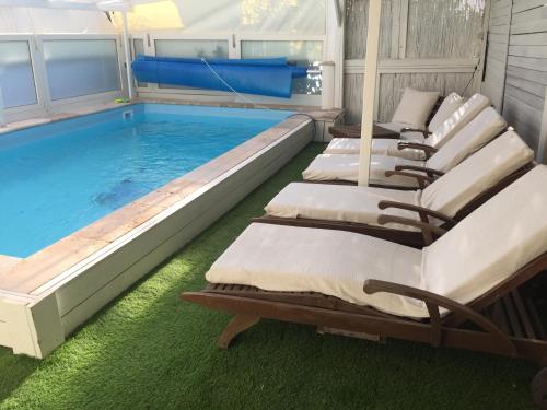 a pool with four chaise lounges next to a swimming pool at Nichochot Provence in Had Nes