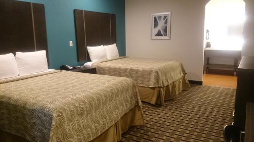 a hotel room with two beds and blue walls at Regency Inn & Suites- NW Houston in Houston