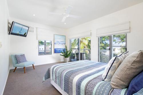a bedroom with a bed and a tv and windows at 53 Hilton Esplanade, Tewantin in Noosaville