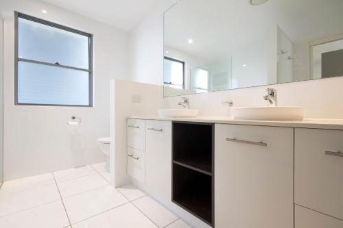 a white bathroom with two sinks and a toilet at 53 Hilton Esplanade, Tewantin in Noosaville