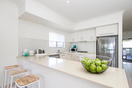 a white kitchen with a bowl of apples on a counter at Tranquil & Modern Riverside Getaway in Noosaville