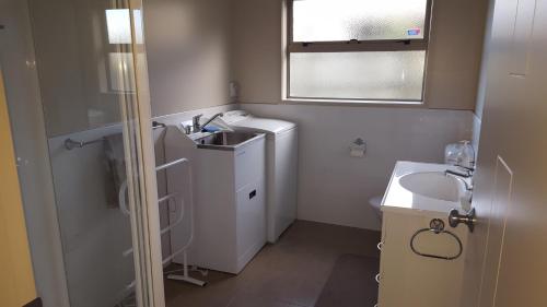 a small bathroom with a sink and a washing machine at Rotorua Views B&B/Apartment in Rotorua