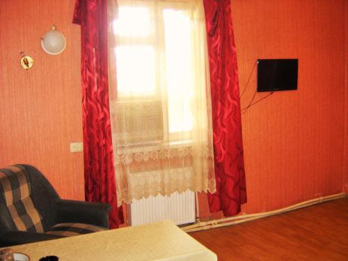 a living room with a window with red curtains at Hotel Lilo near Airport in Tbilisi City