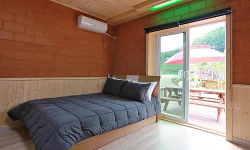 een bed in een kamer met een patio met een parasol bij Rainbow Hwangto Pension in Pyeongchang 