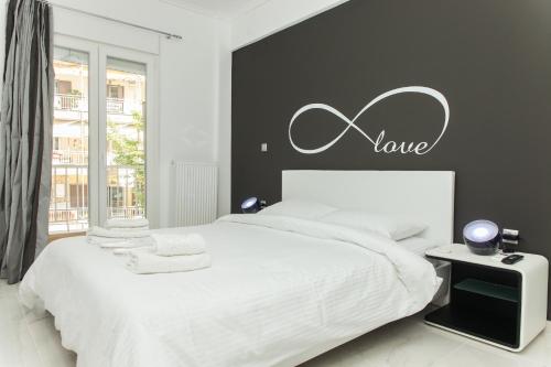 ein Schlafzimmer mit einem weißen Bett mit einem Liebesschild an der Wand in der Unterkunft Route 77 in Thessaloniki