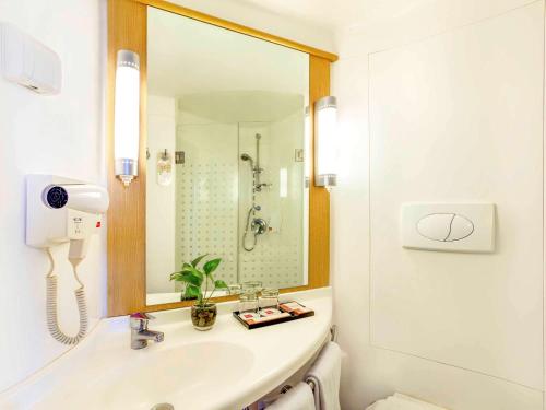 a white bathroom with a sink and a mirror at Ibis Surabaya City Center in Surabaya