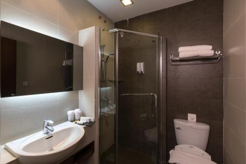 a bathroom with a shower and a toilet and a sink at Swiss Hotel Apartment in Kuala Belait