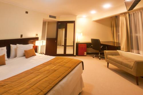 a hotel room with a bed and a desk and a chair at Hotel Costa Pacifico - Suite in Antofagasta