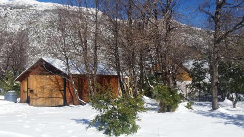 a cabin in the snow with a snow covered mountain at Tatas Haus in Las Trancas
