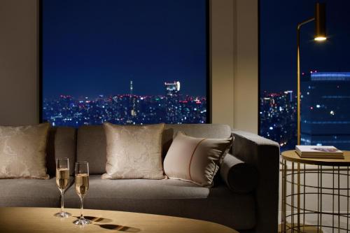 a living room with a couch and two glasses of wine at Keio Plaza Hotel Tokyo Premier Grand in Tokyo