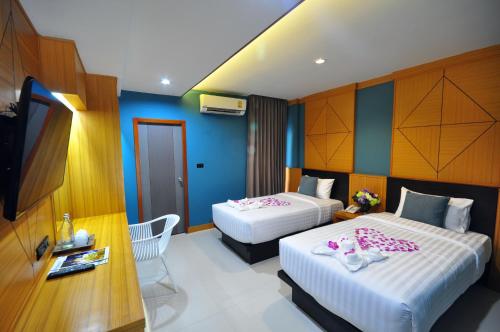 two beds in a hotel room with blue walls at Chiangmai S.P. Hotel in Chiang Mai