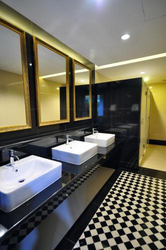 a bathroom with three sinks and a checkered floor at Chiangmai S.P. Hotel in Chiang Mai