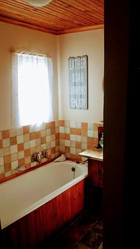 a bathroom with a bath tub and a window at Athanor Cottages in Hogsback