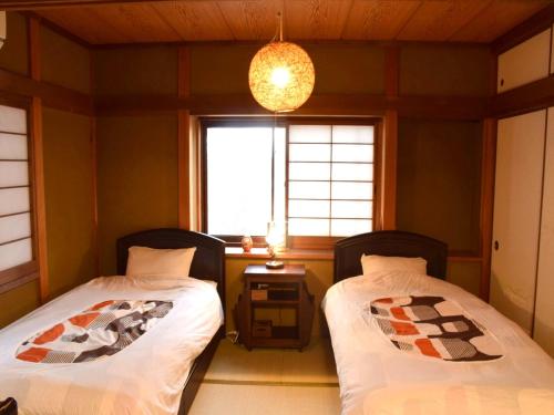 two beds in a room with a window at Guesthouse Higashiyama in Kyoto