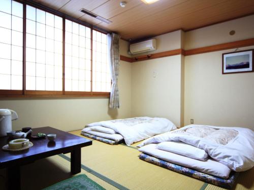 two beds in a room with a table and windows at Komao in Kiso