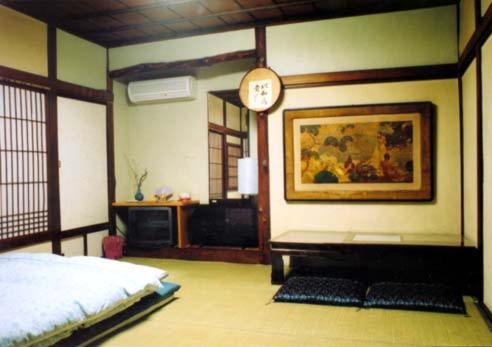 Tama Ryokan في طوكيو: غرفة نوم بسرير وساعة على الحائط