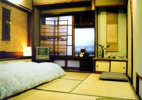 a bedroom with a bed and a window and a television at Tama Ryokan in Tokyo
