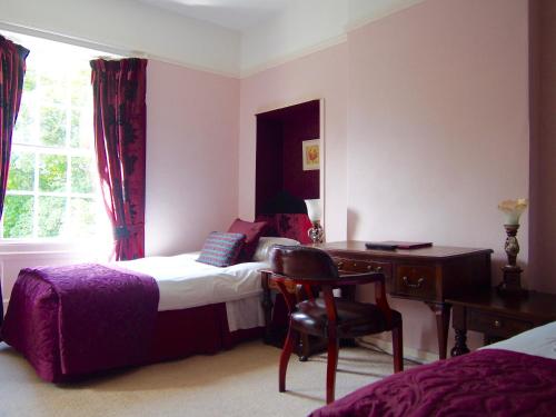 a bedroom with a bed and a desk and a chair at Wrangham House in Filey